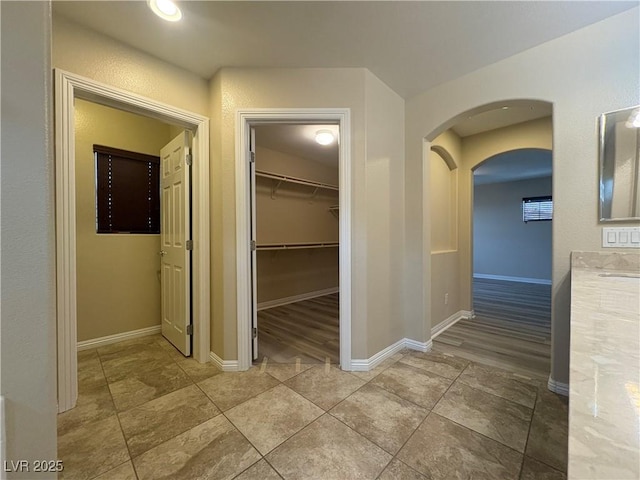 corridor featuring arched walkways and baseboards