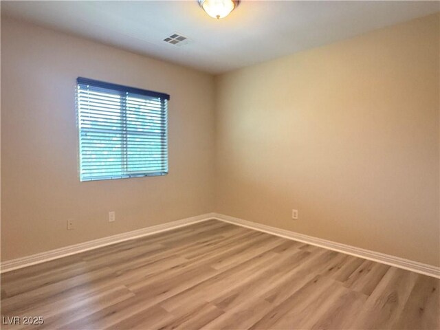 spare room with baseboards, light wood-type flooring, and visible vents