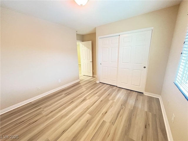 unfurnished bedroom with baseboards, a closet, and light wood finished floors