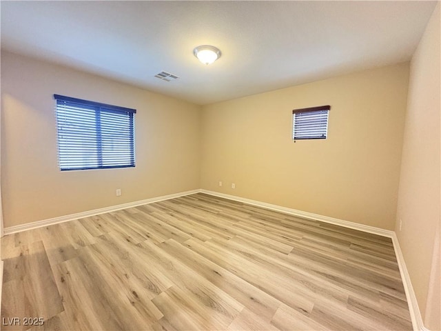 empty room featuring baseboards, visible vents, and light wood-style floors