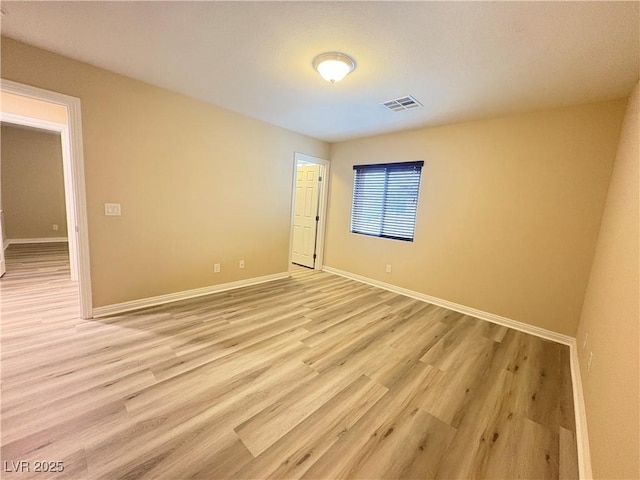 unfurnished room with baseboards, visible vents, and light wood finished floors
