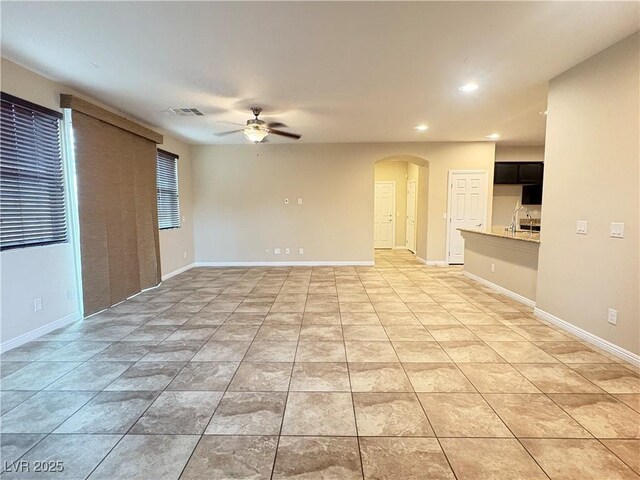 unfurnished living room featuring a ceiling fan, arched walkways, recessed lighting, and baseboards