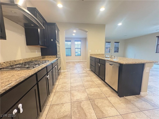 kitchen featuring appliances with stainless steel finishes, arched walkways, a sink, ventilation hood, and light tile patterned flooring
