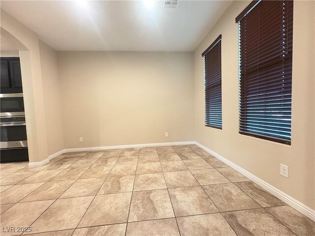 spare room with baseboards and light tile patterned floors