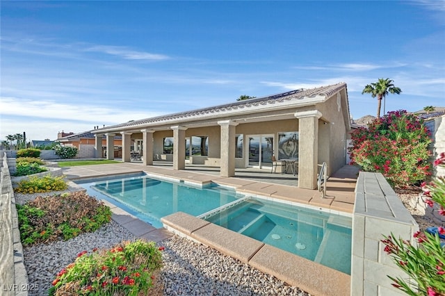 back of house with stucco siding, a pool with connected hot tub, and a patio area