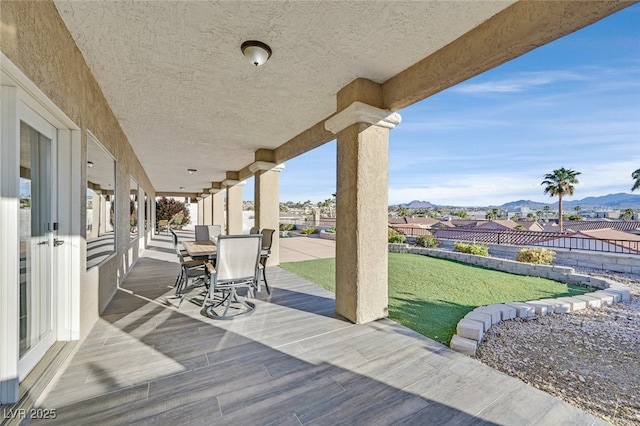 view of patio / terrace with outdoor dining area, a mountain view, and fence