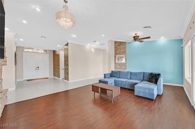 living room with crown molding, ceiling fan, wood finished floors, and visible vents