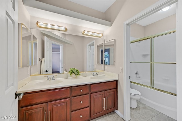 full bathroom featuring double vanity, a sink, shower / bath combination with glass door, and toilet