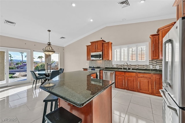 kitchen with backsplash, visible vents, appliances with stainless steel finishes, a sink, and lofted ceiling