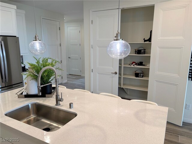 929 Hunter Shores Ave, North Las Vegas, NV 89084 - kitchen with freestanding refrigerator, a sink, wood finished floors, pendant lighting, and white cabinets