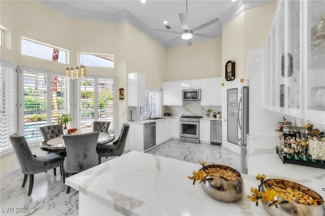 interior space featuring appliances with stainless steel finishes, a high ceiling, light stone counters, and marble finish floor