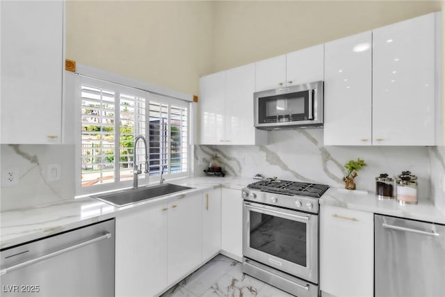 kitchen with decorative backsplash, marble finish floor, white cabinetry, a sink, and appliances with stainless steel finishes