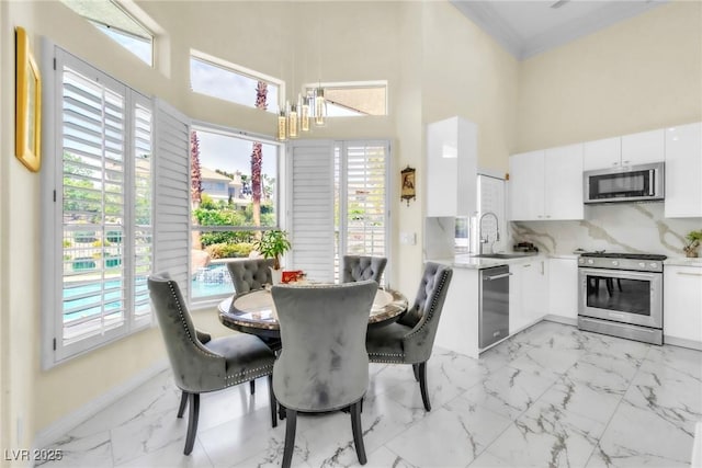 dining area with a healthy amount of sunlight, a high ceiling, marble finish floor, and a chandelier