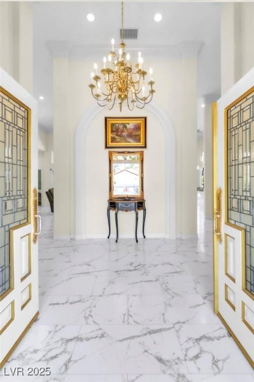 hall featuring visible vents, arched walkways, a high ceiling, and an inviting chandelier