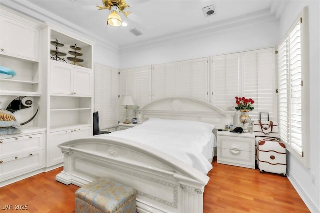 bedroom featuring light wood finished floors, visible vents, and ornamental molding