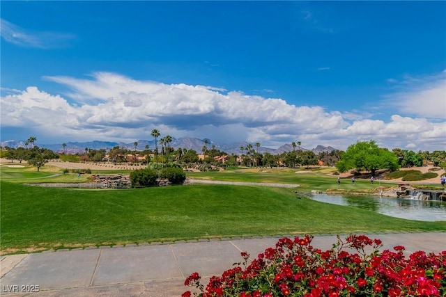 view of community featuring a lawn, a water and mountain view, and golf course view