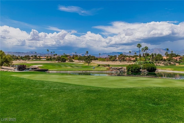 view of community with a yard, view of golf course, and a water and mountain view