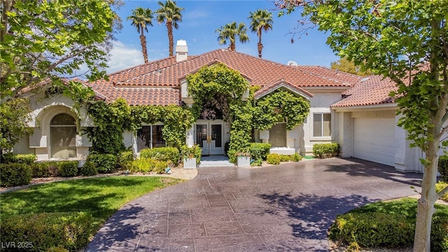 mediterranean / spanish-style house featuring a garage, french doors, a tile roof, and stucco siding