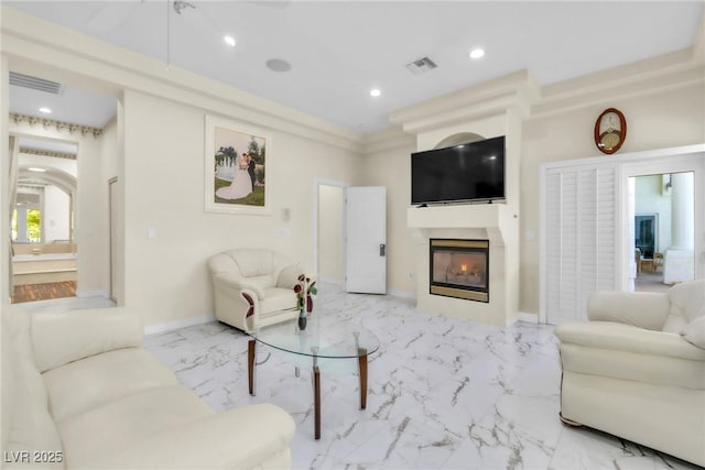 living area featuring visible vents, recessed lighting, marble finish floor, and a glass covered fireplace