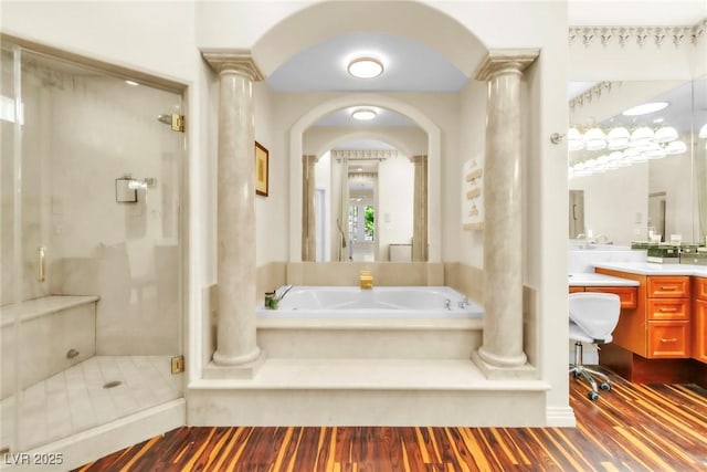 bathroom with vanity, decorative columns, wood finished floors, a bath, and a stall shower