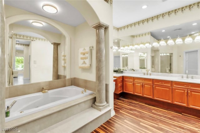 bathroom with ornate columns, a sink, a garden tub, and double vanity