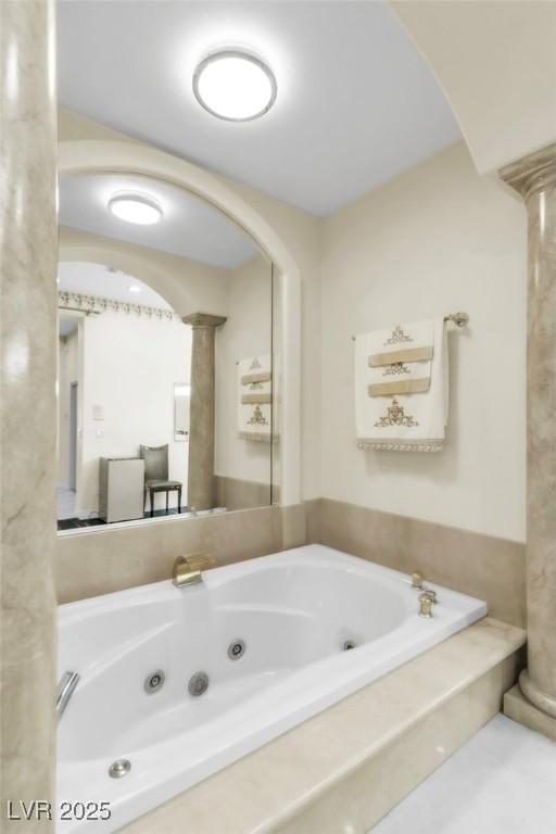 full bathroom with a tub with jets and decorative columns