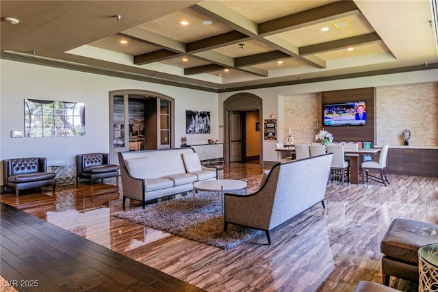 living area with wood finished floors, arched walkways, beam ceiling, and coffered ceiling