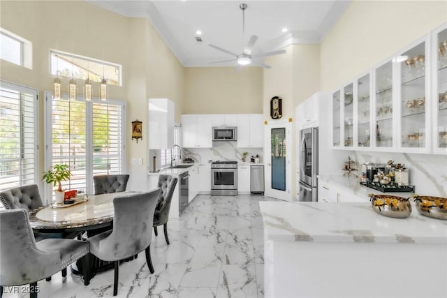 dining room with crown molding, a wealth of natural light, ceiling fan, and a towering ceiling