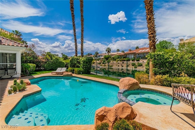 view of swimming pool featuring a pool with connected hot tub and fence