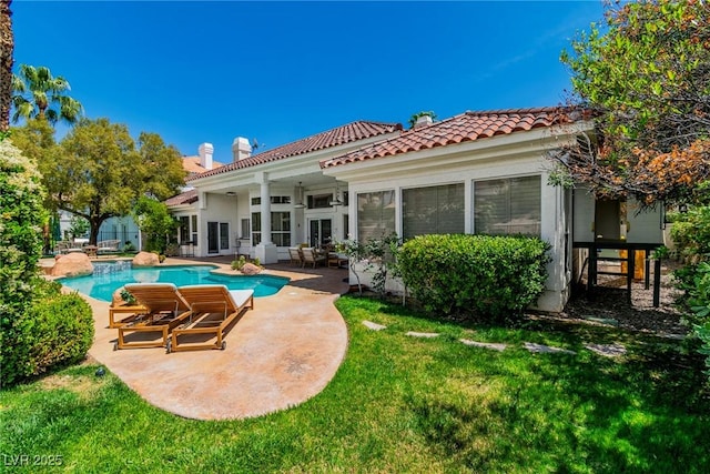 back of property featuring a chimney, a patio area, a tile roof, and an outdoor pool