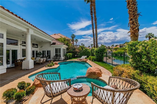 view of pool featuring fence, a pool with connected hot tub, and a patio area