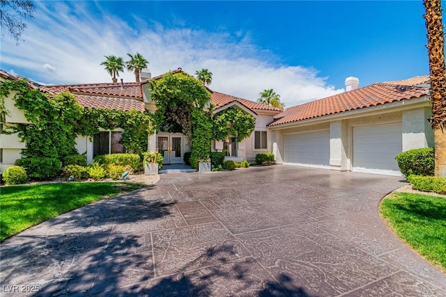 mediterranean / spanish house with a garage, stucco siding, french doors, concrete driveway, and a tile roof