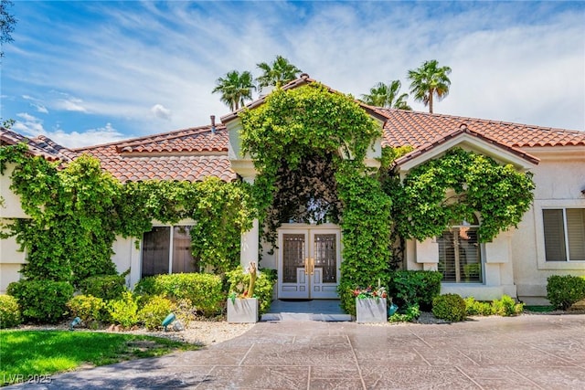 view of front of property with a tiled roof, french doors, and stucco siding