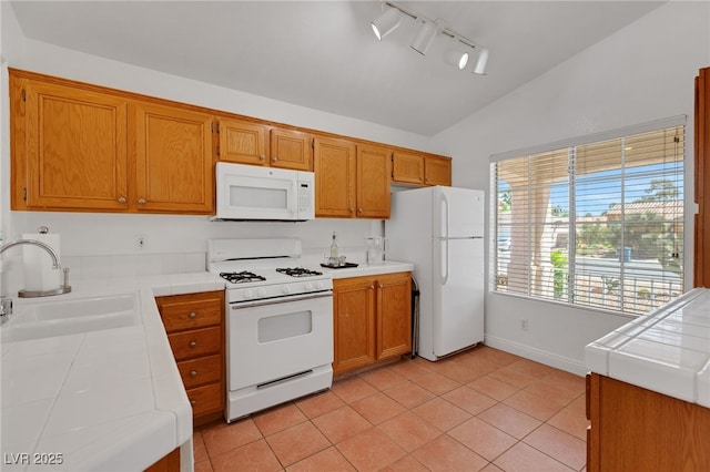 kitchen with white appliances, tile counters, lofted ceiling, a sink, and light tile patterned flooring