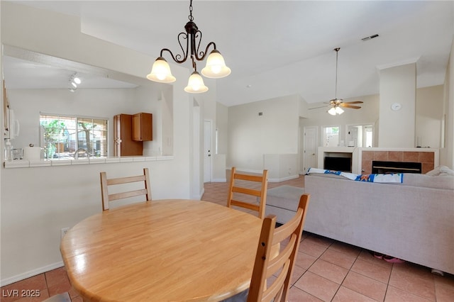 dining area with light tile patterned flooring, plenty of natural light, a tiled fireplace, and a ceiling fan