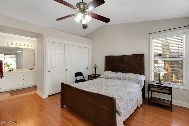 bedroom with lofted ceiling, light wood-style flooring, multiple windows, a closet, and baseboards