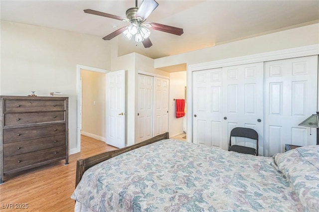 bedroom featuring two closets, light wood-style floors, baseboards, ceiling fan, and lofted ceiling