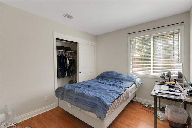 bedroom featuring wood finished floors, baseboards, and a closet