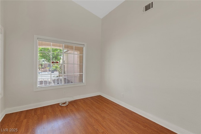 empty room with baseboards, wood finished floors, and lofted ceiling
