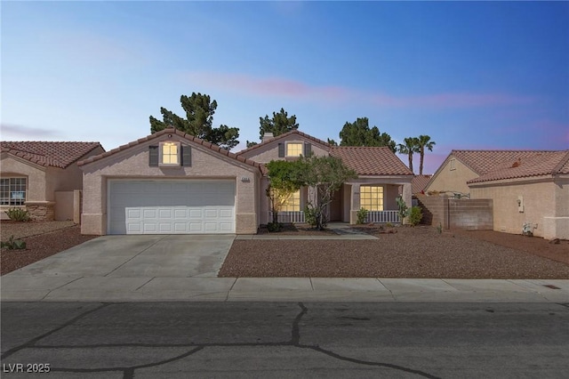view of front of house featuring a tiled roof, concrete driveway, an attached garage, fence, and stucco siding