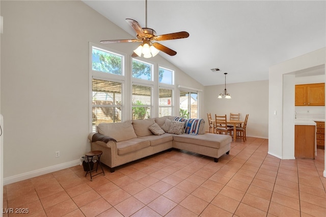 living area with high vaulted ceiling, light tile patterned flooring, healthy amount of natural light, a ceiling fan, and a chandelier
