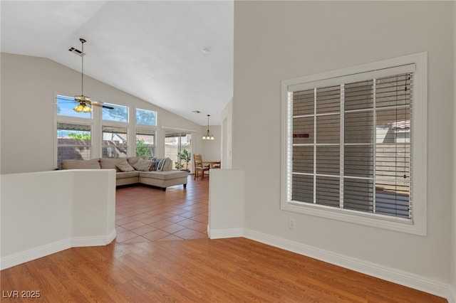 living room featuring vaulted ceiling, light wood-style floors, a ceiling fan, and baseboards