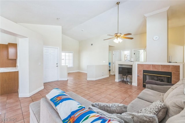 living room with light tile patterned floors, high vaulted ceiling, ceiling fan, a fireplace, and baseboards