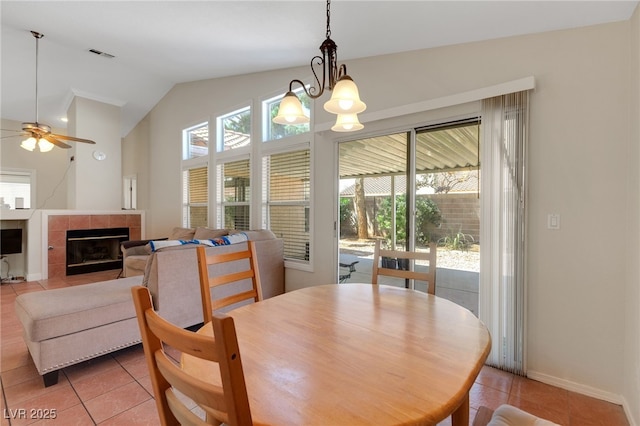 dining area featuring light tile patterned floors, vaulted ceiling, ceiling fan, a fireplace, and baseboards