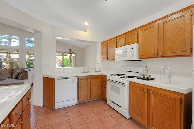 kitchen featuring white appliances, tile countertops, lofted ceiling, a sink, and light tile patterned floors
