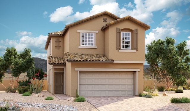 mediterranean / spanish-style house featuring decorative driveway, a garage, stucco siding, and a tiled roof