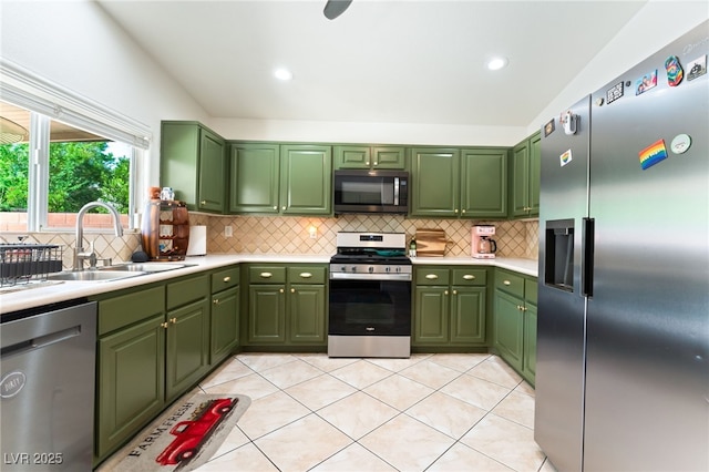 kitchen with backsplash, a sink, light countertops, green cabinets, and stainless steel appliances