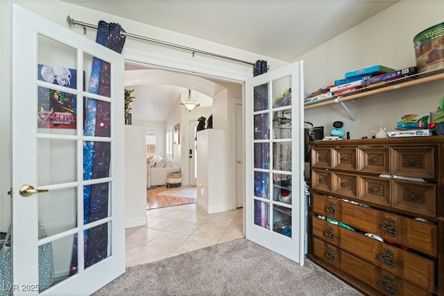 interior space featuring french doors, arched walkways, tile patterned floors, and carpet flooring