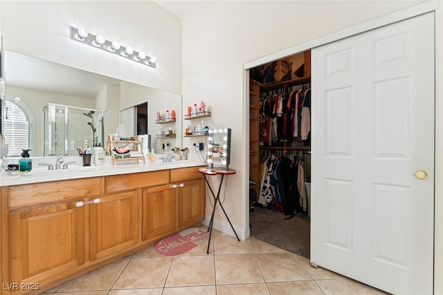 bathroom featuring double vanity, tile patterned floors, a shower stall, and a sink