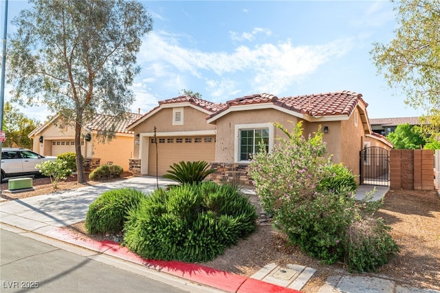 mediterranean / spanish home with a garage, stucco siding, a gate, concrete driveway, and a tiled roof